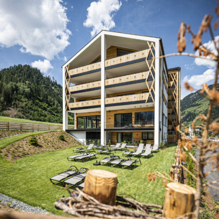 carpe solem Rauris. Hotel Resort in Rauris in Salzburg. Außenansicht im Sommer mit Wiese und umgebender Natur.