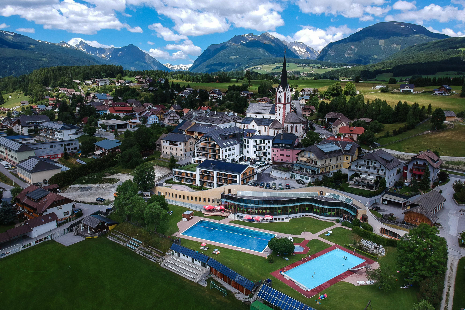 carpe solem Hotel direkt im Ort von Mariapfarr. Im Hintergrund die Wallfahrtsbasilika des Ortes und die Berwelt und Landschaft des Biosphärenparks Salzburger Lungau.