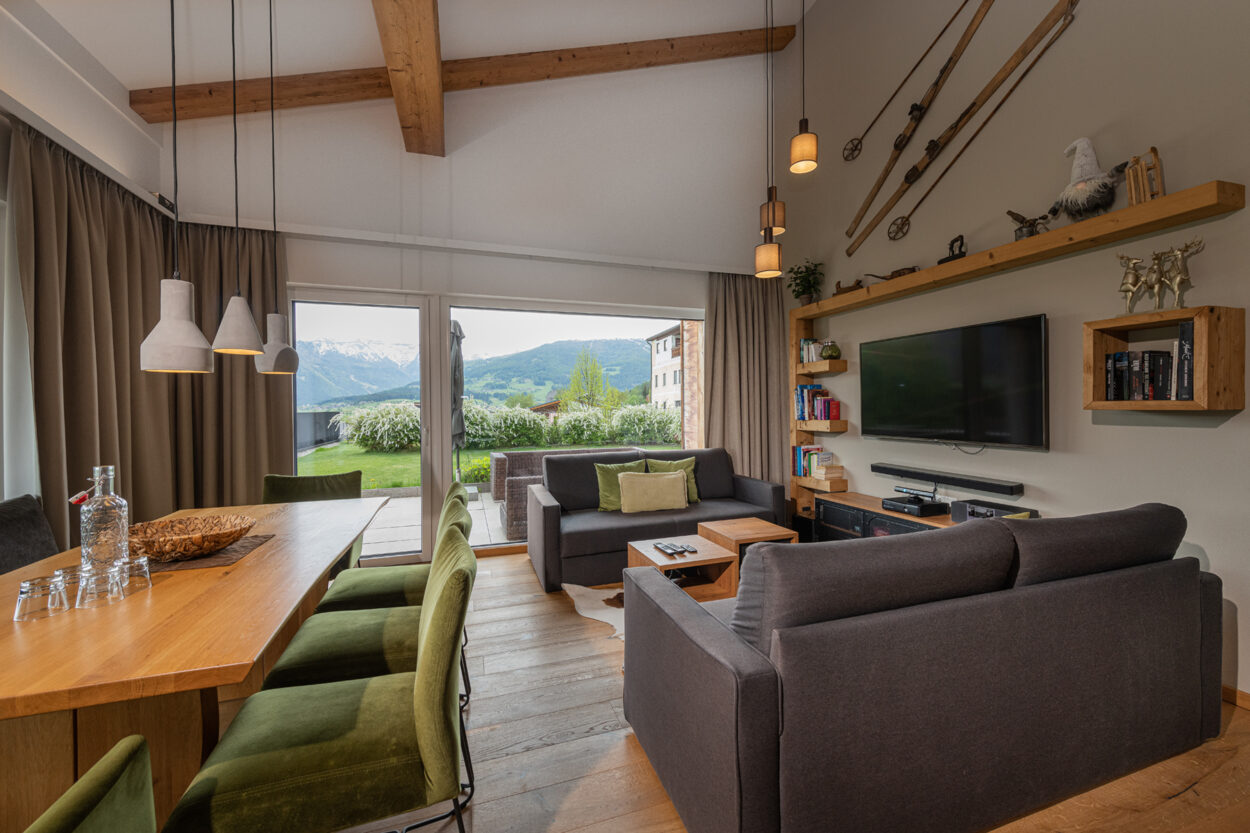 Apartment im Hotel Resort carpe solem in Mariapfarr. Innenansicht eines Wohnzimmers mit hochwertiger Ausstattung und Esstisch mit Platz für 8 Personen für einen Familienurlaub im Salzburger Lungau.