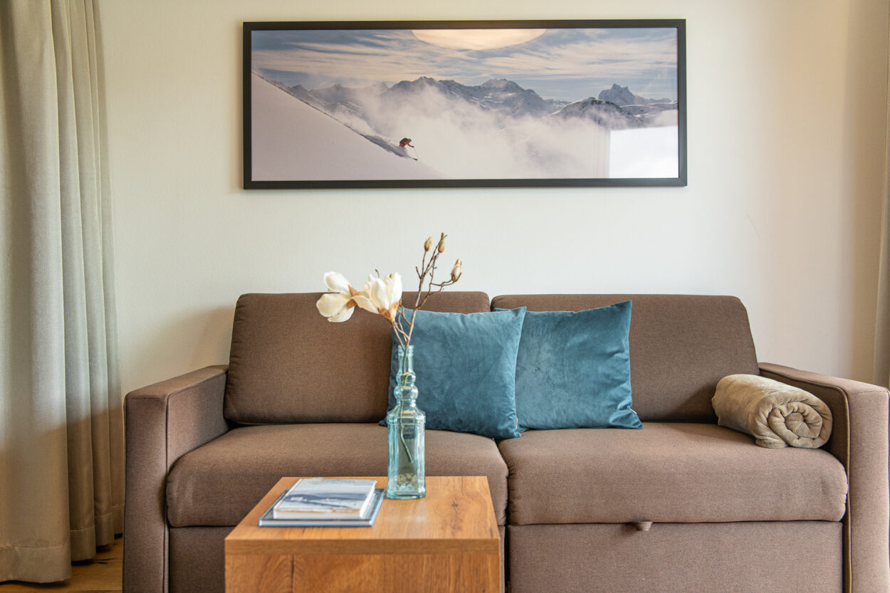 Apartment im Hotelresort carpe solem Mariapfarr im Salzburger Lungau. Wohnzimmer mit Sofa und Bild mit Bergpanorama.